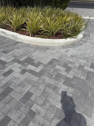 Grey herringbone pavers around a curved kerbed planter bed