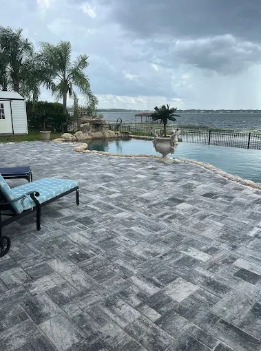 Grey travertine paver pool deck on a lakefront property in Orlando