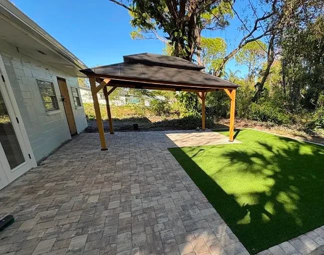 Paver patio with a timber gazebo beside an artificial turf lawn