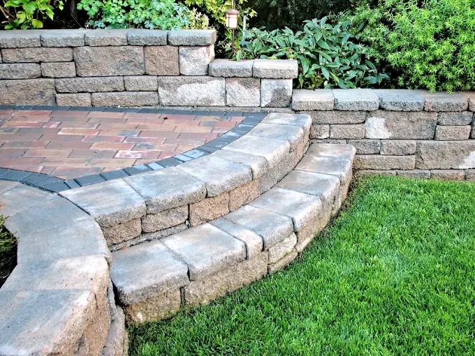 Curved paver steps and a stacked block retaining wall beside a lawn